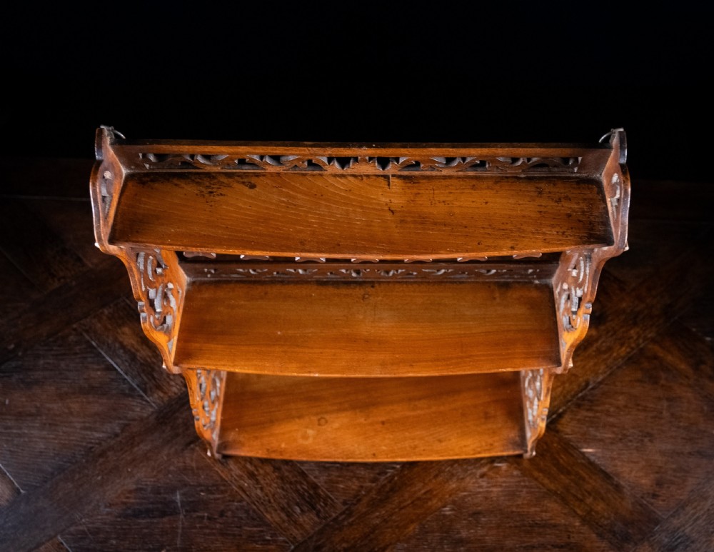 A three-tier Victorian mahogany wall shelf featuring open fretwork sides, pierced scroll decoration, and serrated apron trim. View XI