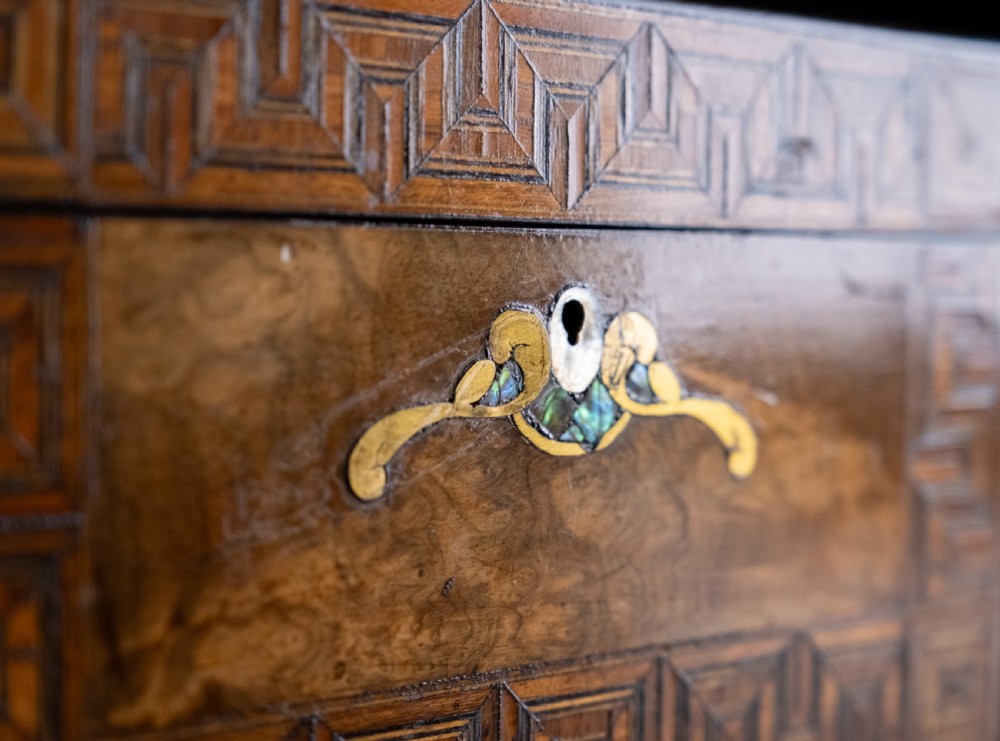 A rectangular walnut tea caddy featuring geometric parquetry borders, a mother-of-pearl escutcheon, and brass inlay on a dark wooden surface. View III
