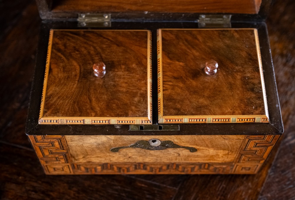 A rectangular walnut tea caddy featuring geometric parquetry borders, a mother-of-pearl escutcheon, and brass inlay on a dark wooden surface. View XI