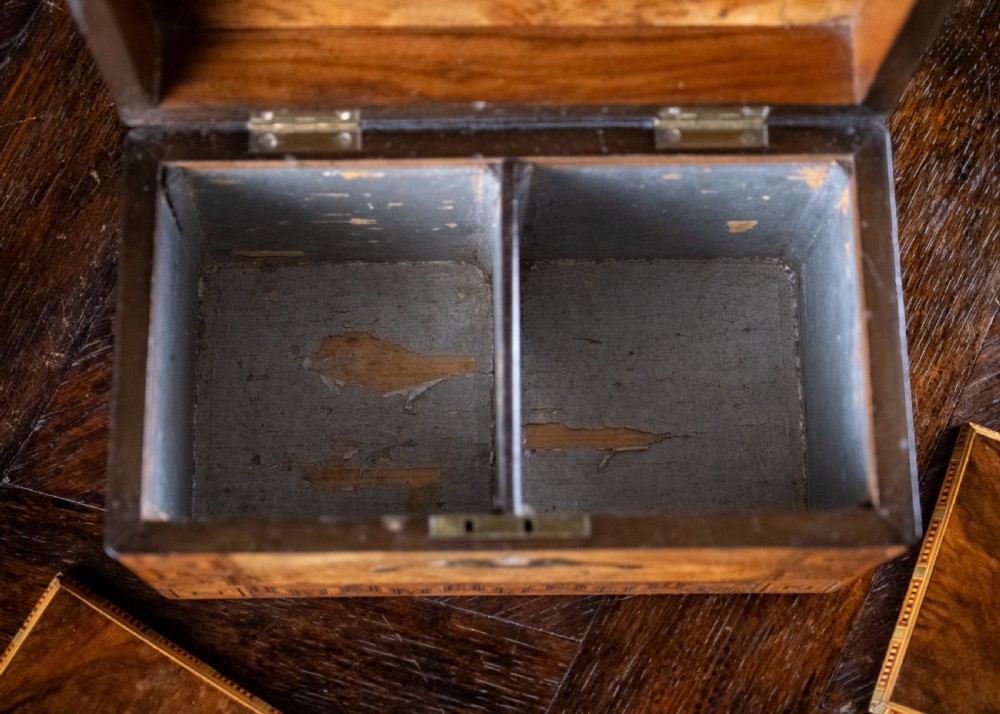 A rectangular walnut tea caddy featuring geometric parquetry borders, a mother-of-pearl escutcheon, and brass inlay on a dark wooden surface. View XII