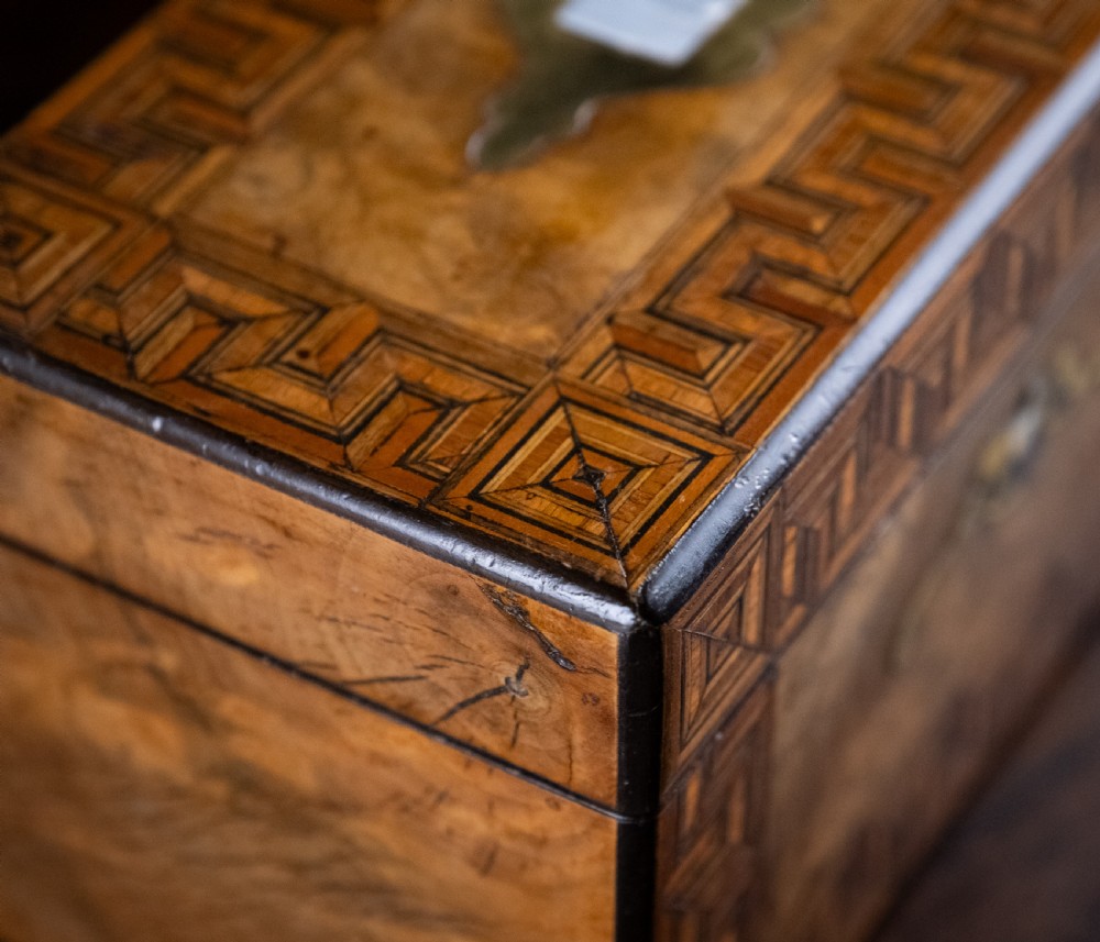 A rectangular walnut tea caddy featuring geometric parquetry borders, a mother-of-pearl escutcheon, and brass inlay on a dark wooden surface. View XIX