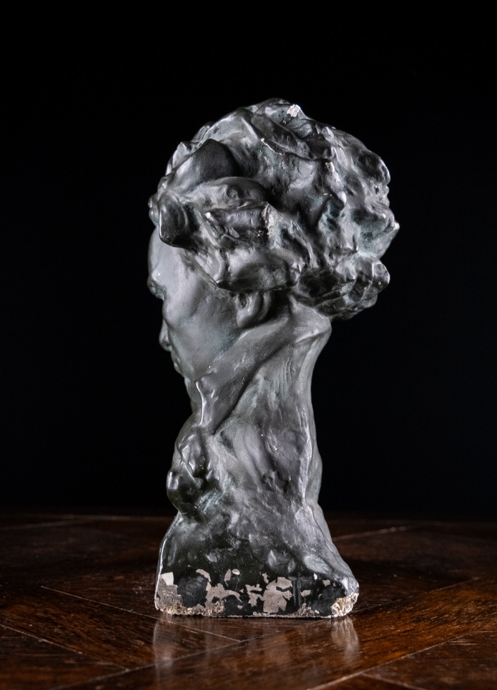 A dark bronze-coloured painted plaster bust depicting composer Ludwig van Beethoven with detailed hair and a dramatic collar on a square base. View IX