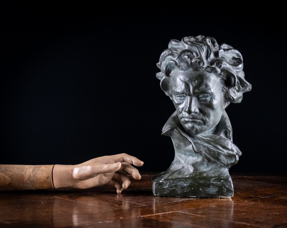 A dark bronze-coloured painted plaster bust depicting composer Ludwig van Beethoven with detailed hair and a dramatic collar on a square base. View XIII