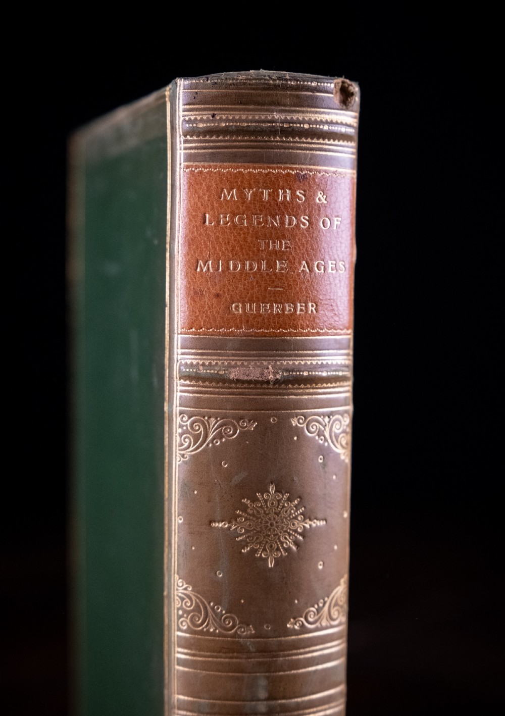 An upright antique book titled Myths and Legends of the Middle Ages with a brown leather spine featuring gilt tooling and green cloth covers. View II
