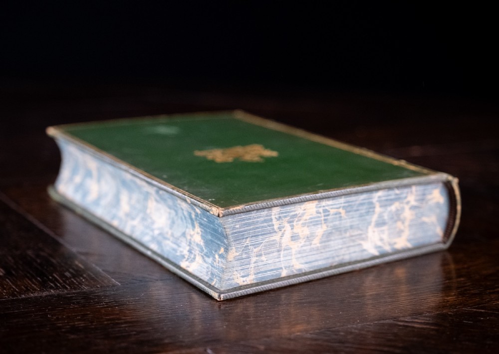 An upright antique book titled Myths and Legends of the Middle Ages with a brown leather spine featuring gilt tooling and green cloth covers. View V