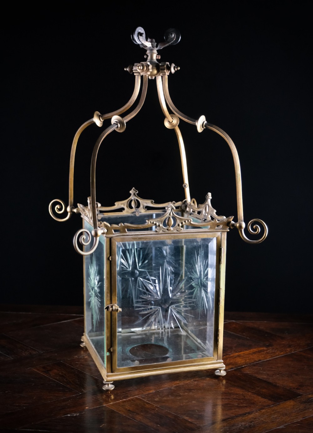 An Edwardian brass square-framed hall lantern featuring bevelled glass panels with starburst cuts and scrollwork hanging arms. View II