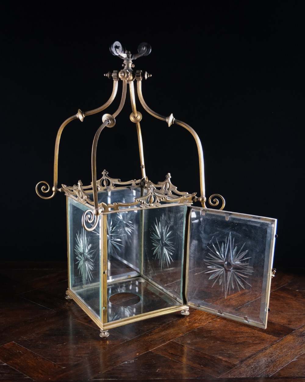 An Edwardian brass square-framed hall lantern featuring bevelled glass panels with starburst cuts and scrollwork hanging arms. View III