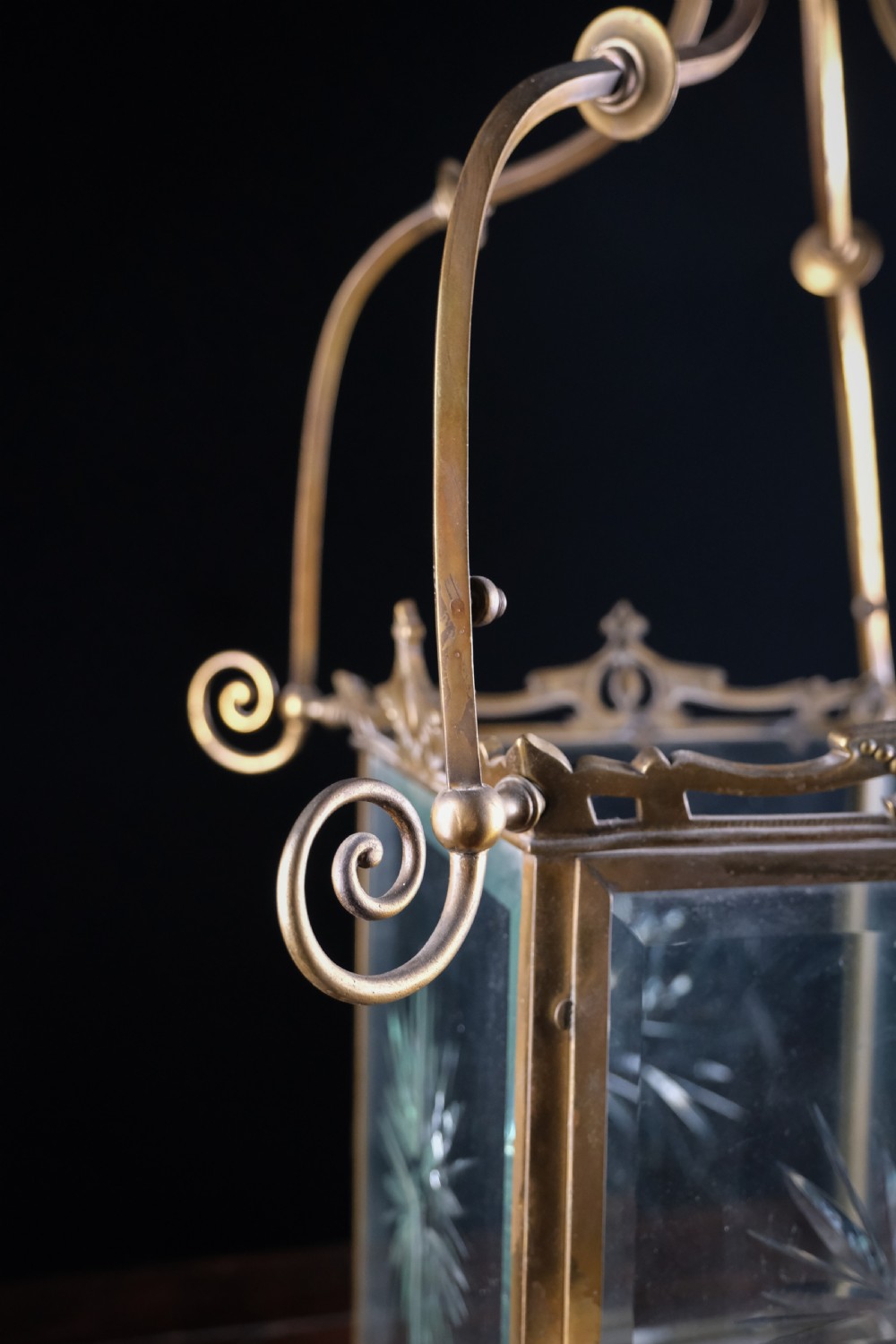 An Edwardian brass square-framed hall lantern featuring bevelled glass panels with starburst cuts and scrollwork hanging arms. View IV