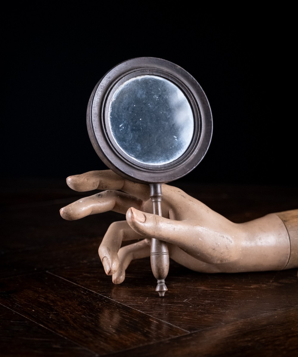 A circular Regency double-sided hand mirror with a turned dark timber frame, baluster handle, and aged mirror plate. View IV
