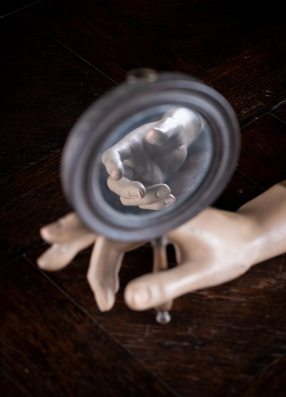 A circular Regency double-sided hand mirror with a turned dark timber frame, baluster handle, and aged mirror plate. View V