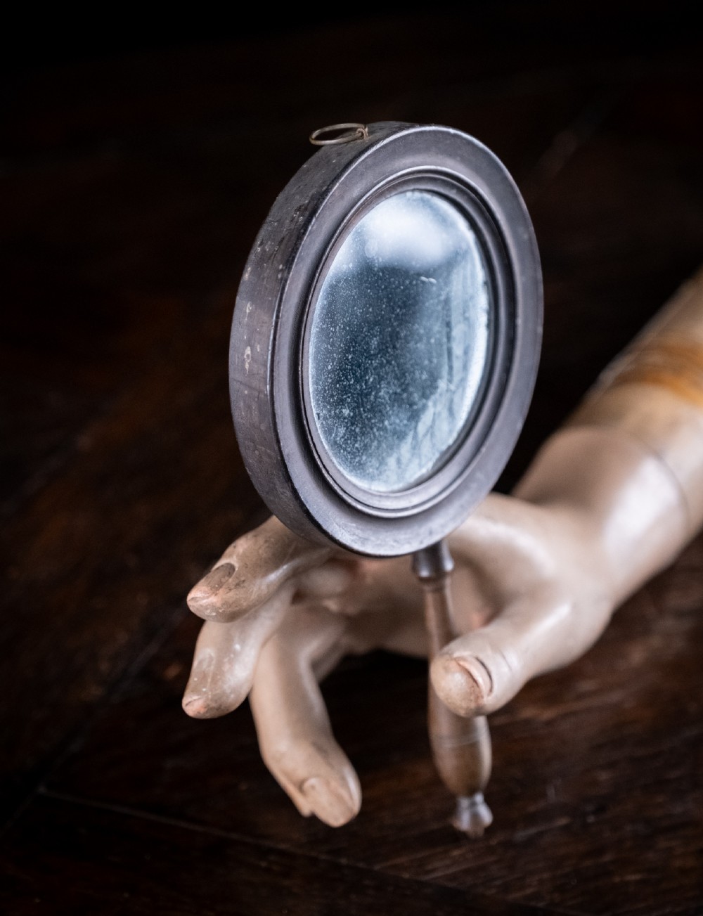 A circular Regency double-sided hand mirror with a turned dark timber frame, baluster handle, and aged mirror plate. View VI