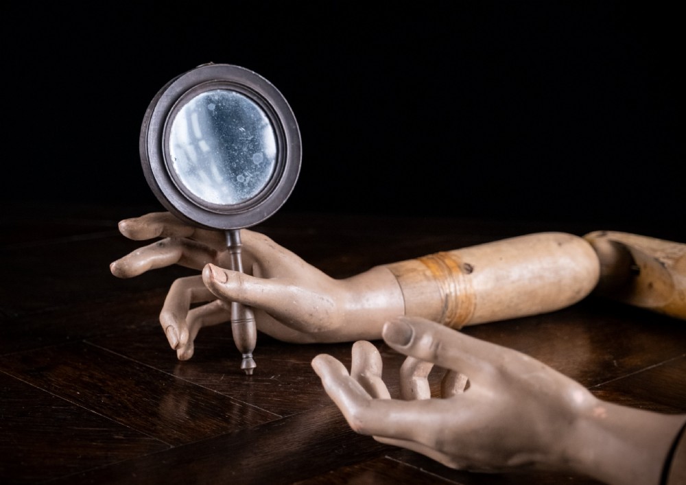 A circular Regency double-sided hand mirror with a turned dark timber frame, baluster handle, and aged mirror plate. View VIII