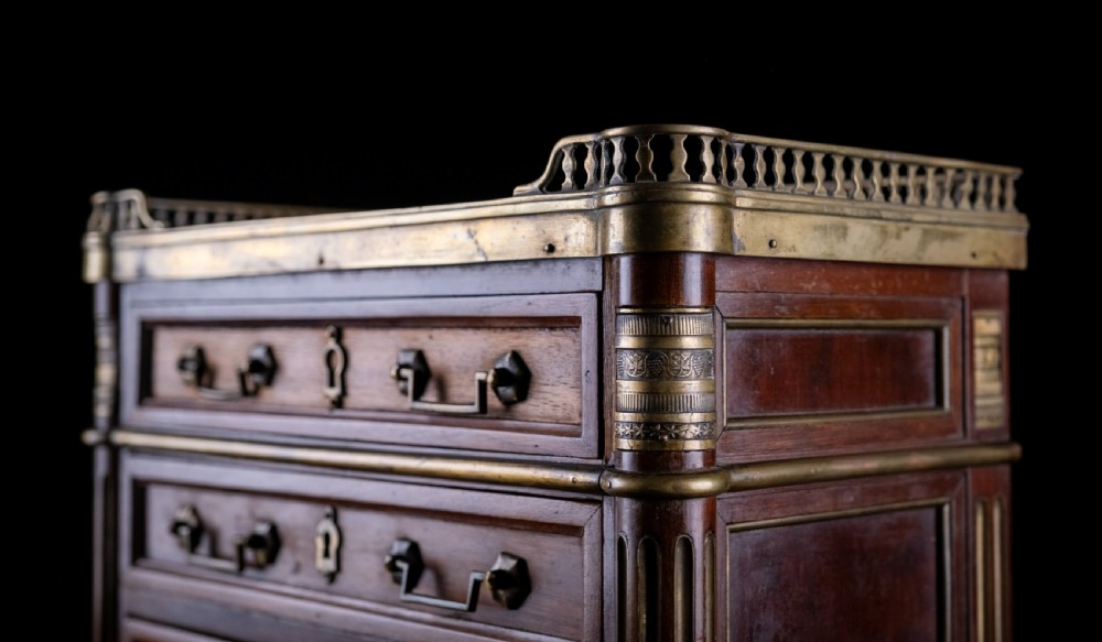 A miniature Louis XVI style mahogany three-drawer commode featuring brass mounts, fluted corner columns, and a gallery top inset with marble. View X