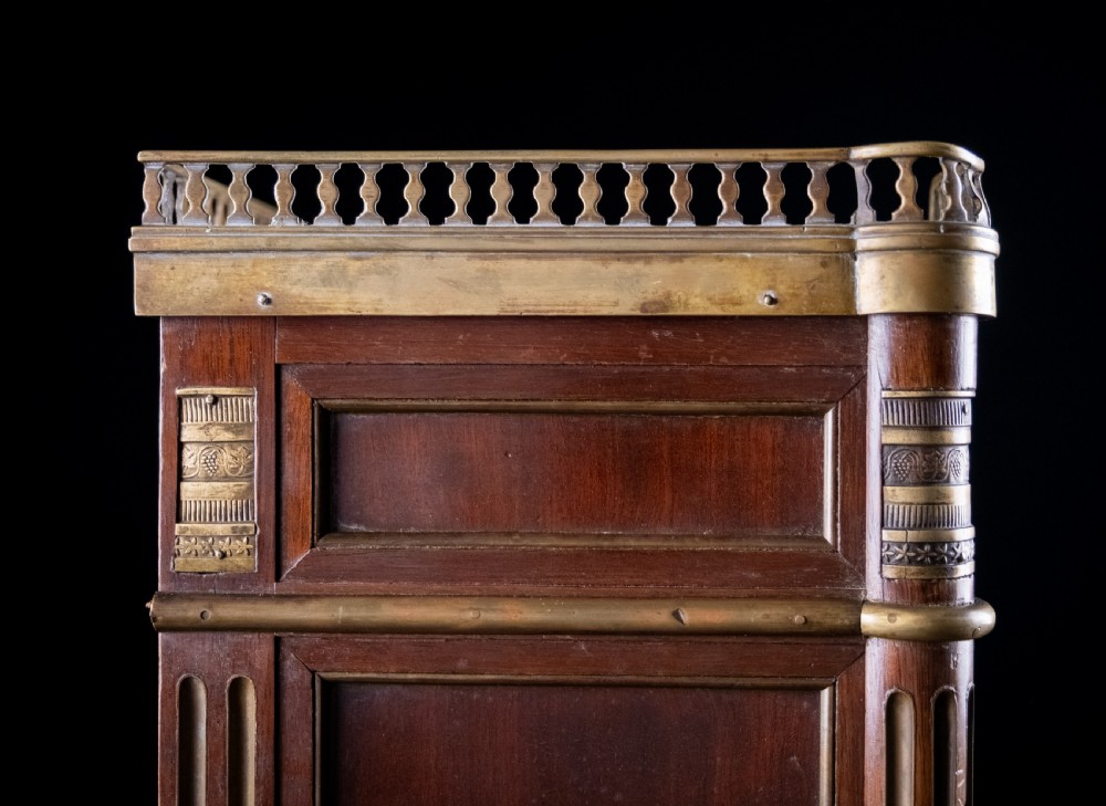 A miniature Louis XVI style mahogany three-drawer commode featuring brass mounts, fluted corner columns, and a gallery top inset with marble. View XVII
