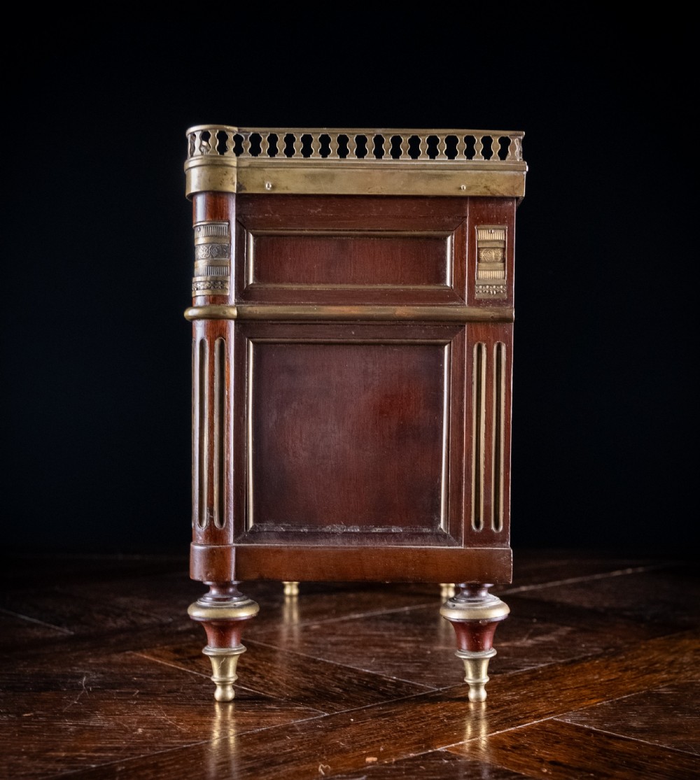 A miniature Louis XVI style mahogany three-drawer commode featuring brass mounts, fluted corner columns, and a gallery top inset with marble. View XIX