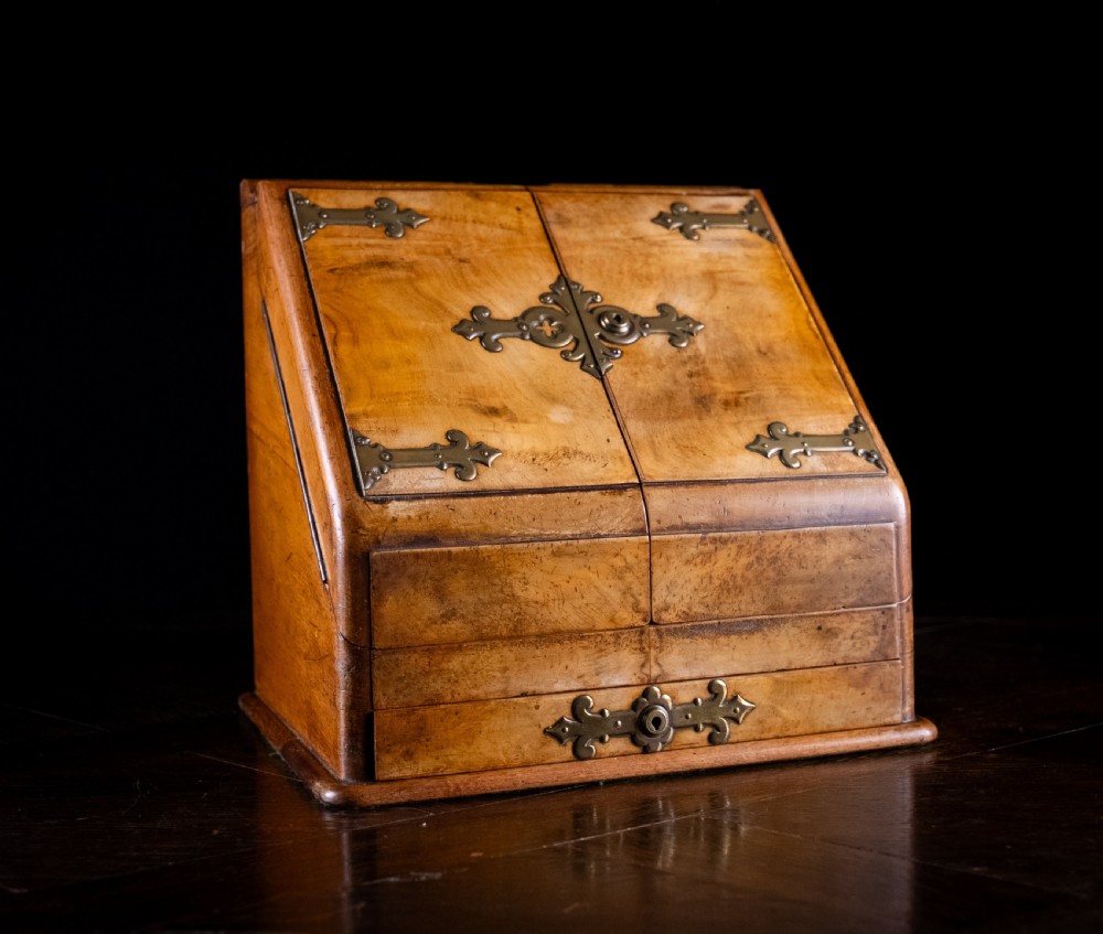A late nineteenth-century Victorian walnut slope-front stationery cabinet featuring ornate brass strapwork mounts and lock escutcheons.