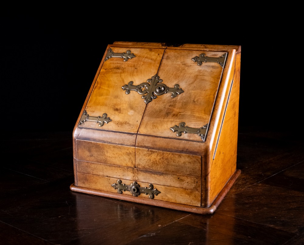 A late nineteenth-century Victorian walnut slope-front stationery cabinet featuring ornate brass strapwork mounts and lock escutcheons. View V