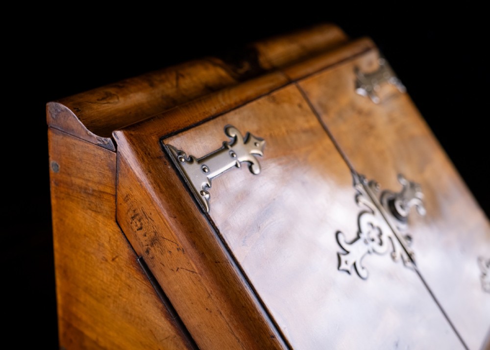 A late nineteenth-century Victorian walnut slope-front stationery cabinet featuring ornate brass strapwork mounts and lock escutcheons. View VI