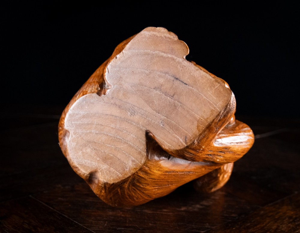 A hand-carved warm brown wooden sculpture depicting a seated monkey with chiselled fur details and dark eyes. View XIV
