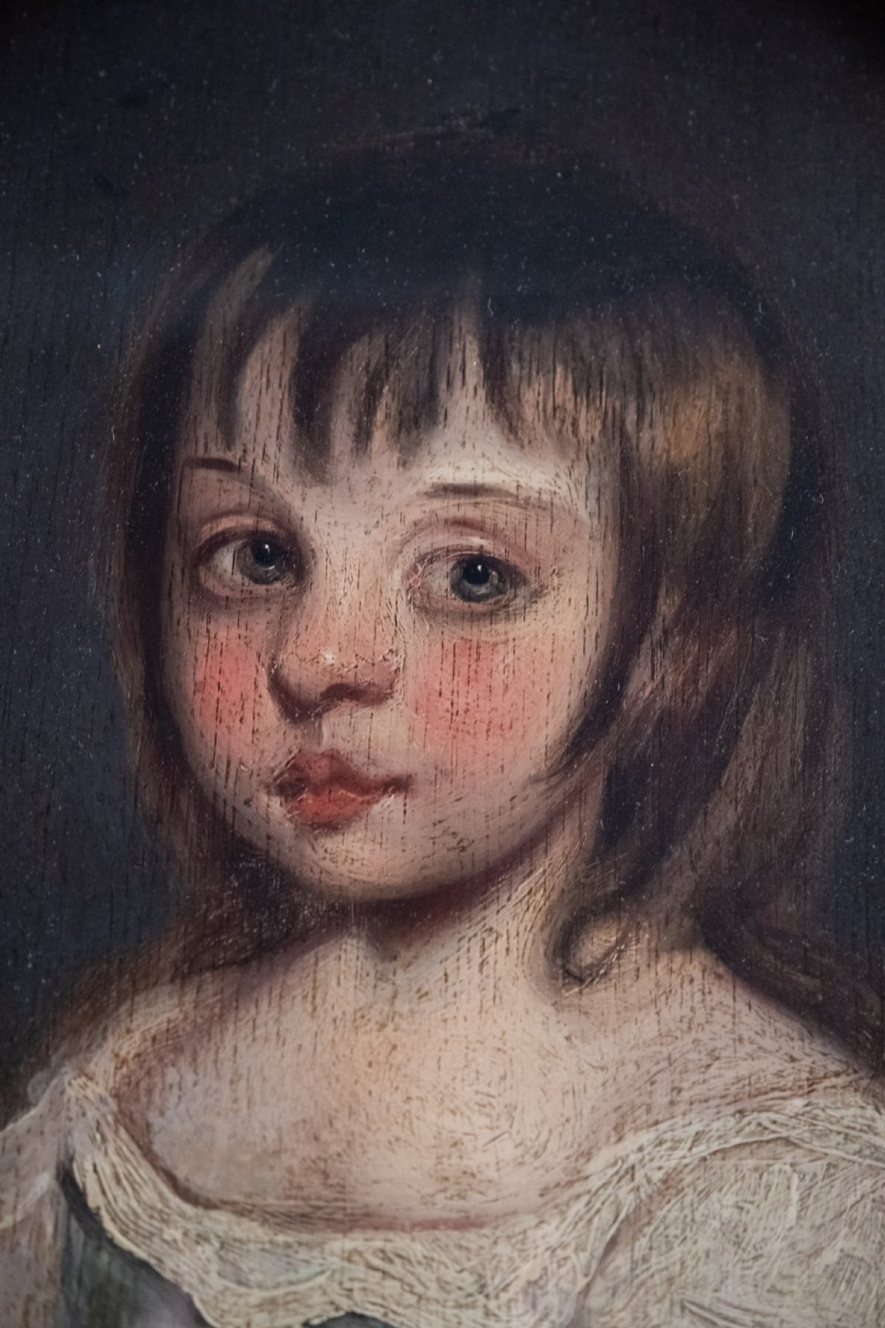 An 18th-century oval portrait painting depicting a young girl with brown hair wearing a blue and white dress within a gilded frame. View III