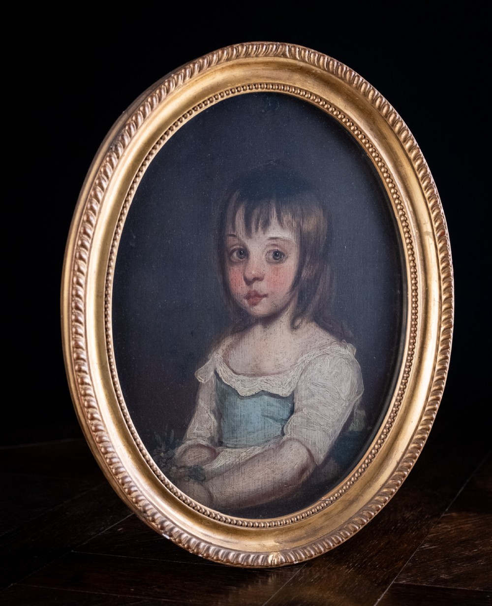 An 18th-century oval portrait painting depicting a young girl with brown hair wearing a blue and white dress within a gilded frame. View V