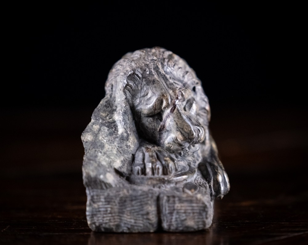 A carved dark serpentine stone sculpture depicting the recumbent Lion of Lucerne resting on an integral rectangular stone base. View VIII