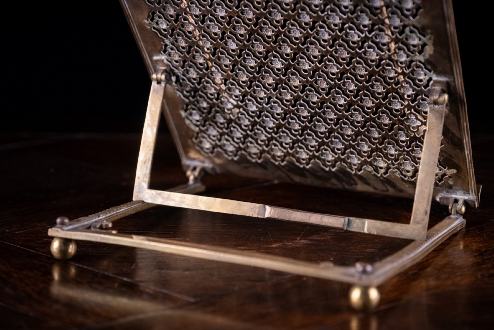 An antique brass folding book rest featuring an intricate pierced fretwork pattern, adjustable easel backing, and weighted page holder cords. View XI