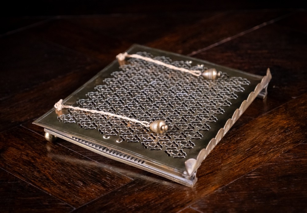 An antique brass folding book rest featuring an intricate pierced fretwork pattern, adjustable easel backing, and weighted page holder cords. View XIV