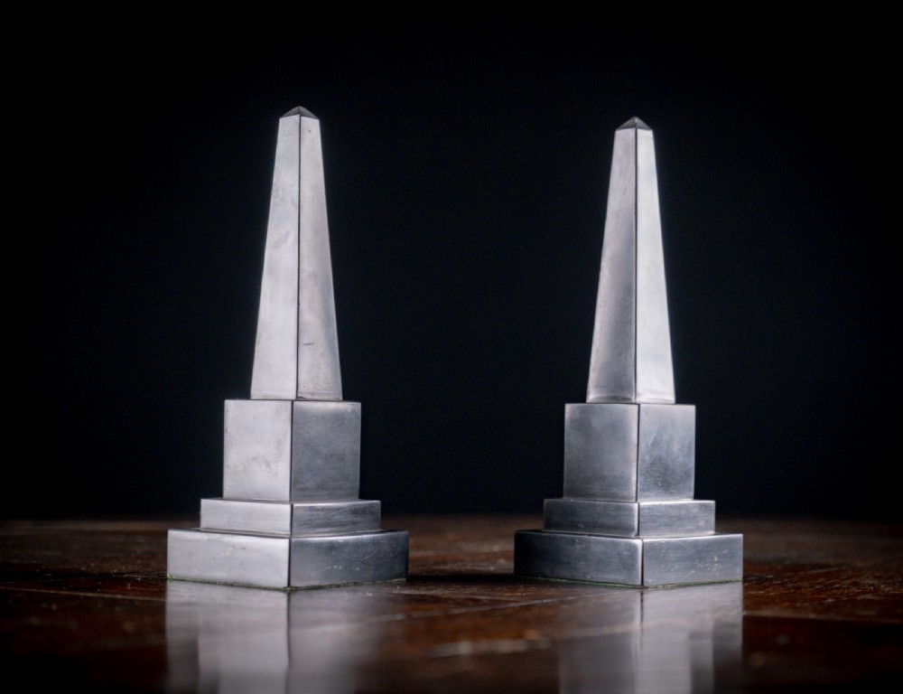 A pair of 19th-century black marble obelisks featuring tapered four-sided shafts set on stepped square plinth bases.