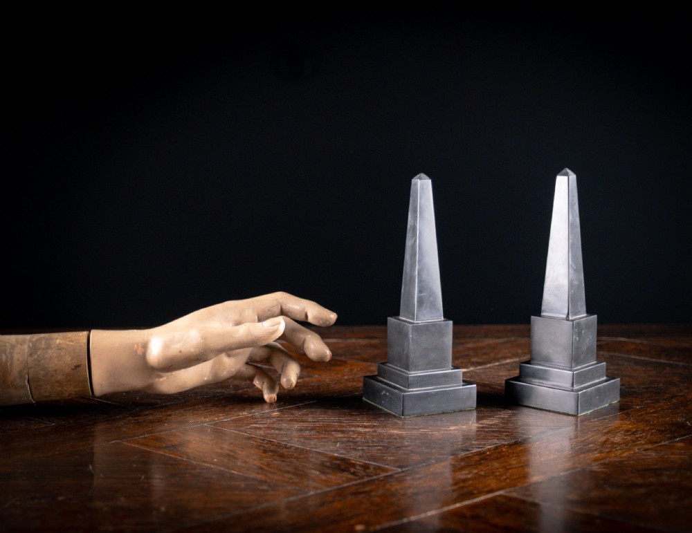 A pair of 19th-century black marble obelisks featuring tapered four-sided shafts set on stepped square plinth bases. View VI