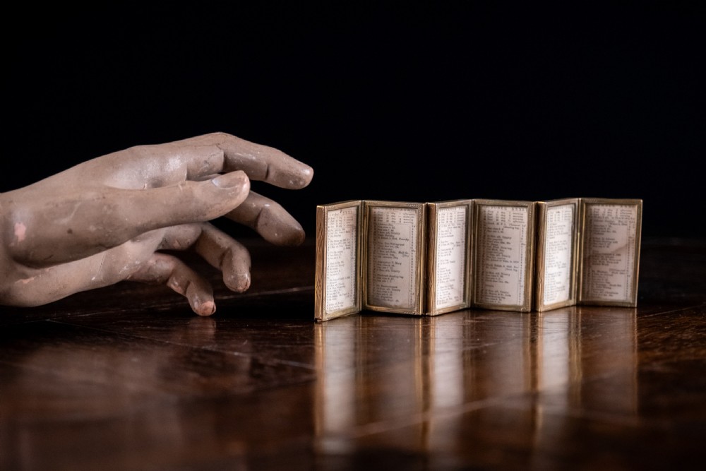 A nineteenth-century six-fold miniature brass frame holding printed paper London almanac sheets dated 1878. View V
