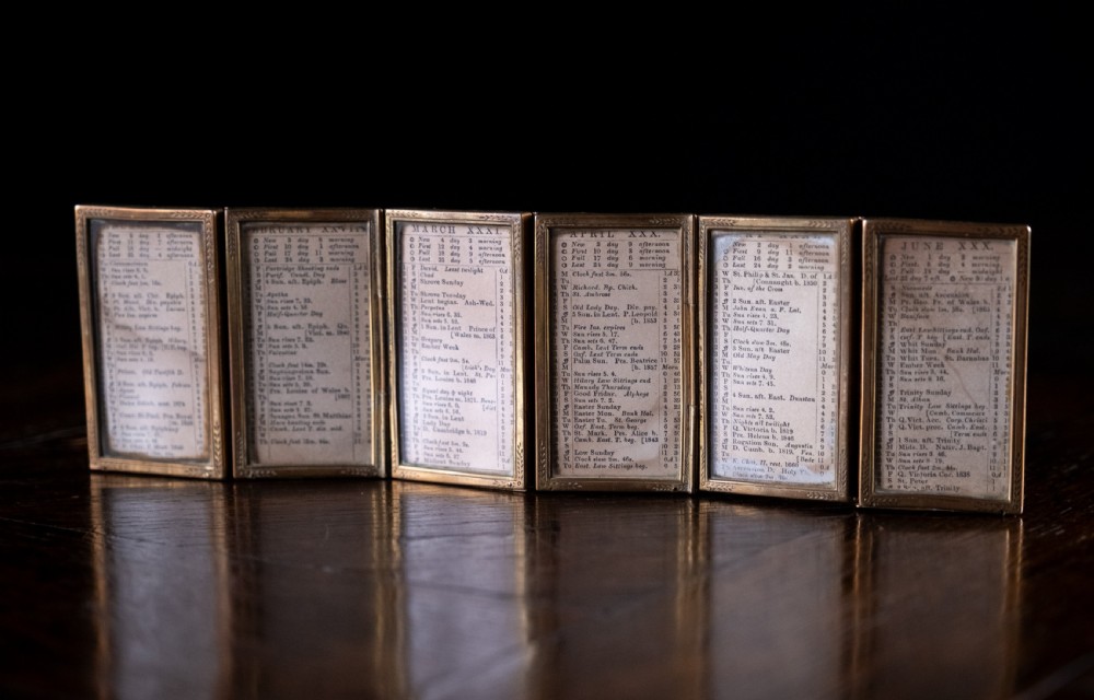 A nineteenth-century six-fold miniature brass frame holding printed paper London almanac sheets dated 1878. View X