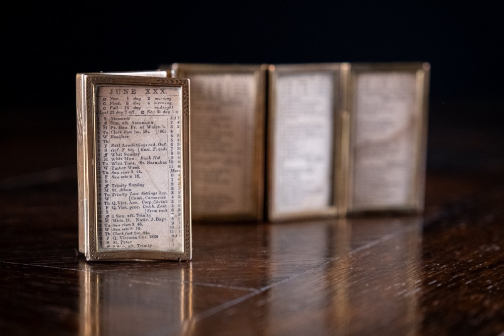 A nineteenth-century six-fold miniature brass frame holding printed paper London almanac sheets dated 1878. View XI
