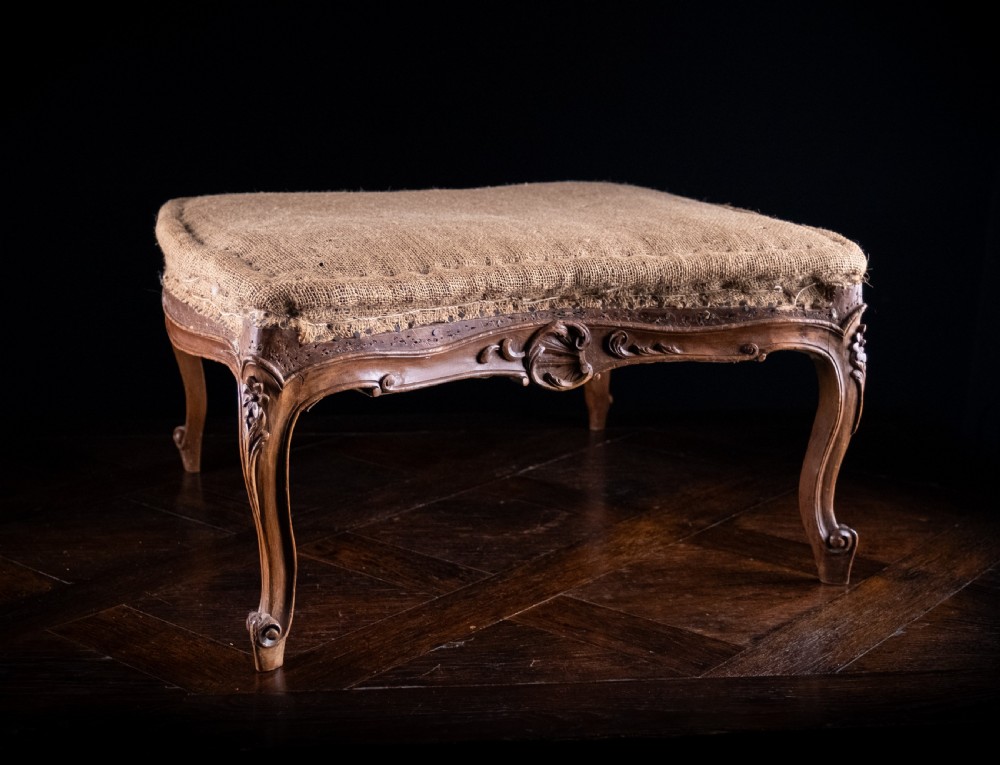 A low rectangular Louis XV style footstool featuring a carved beech frame, cabriole legs, shell motifs, and hessian upholstery. View II