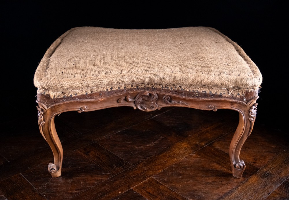 A low rectangular Louis XV style footstool featuring a carved beech frame, cabriole legs, shell motifs, and hessian upholstery. View IV