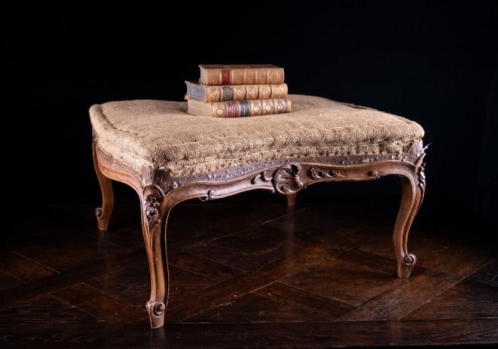A low rectangular Louis XV style footstool featuring a carved beech frame, cabriole legs, shell motifs, and hessian upholstery. View V