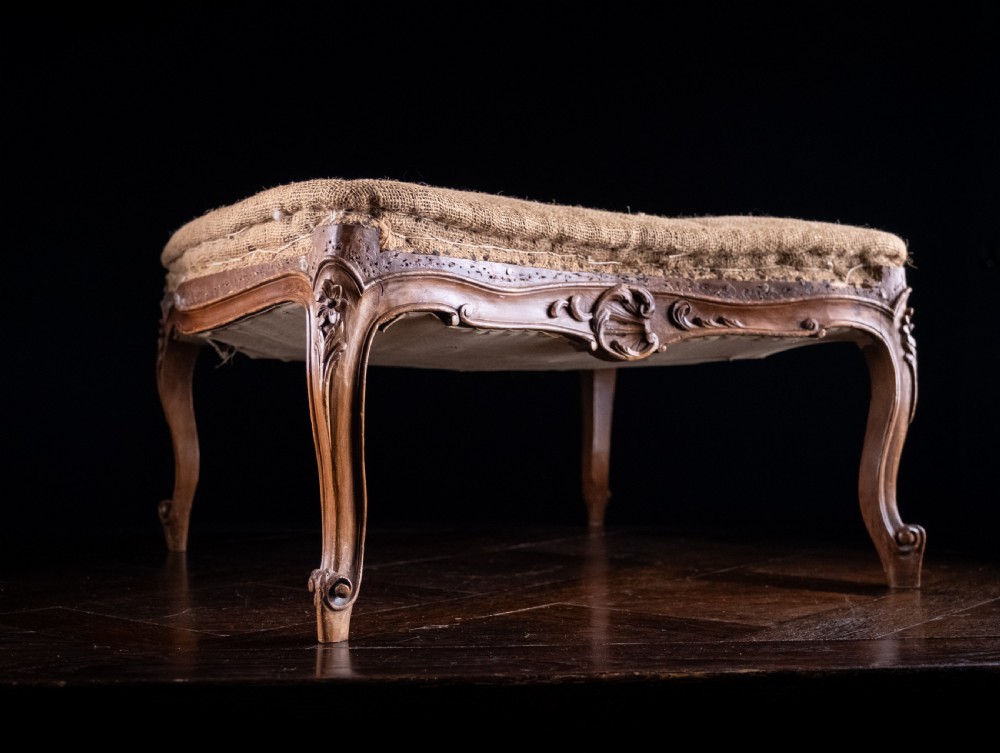A low rectangular Louis XV style footstool featuring a carved beech frame, cabriole legs, shell motifs, and hessian upholstery. View VI