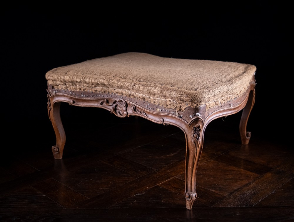 A low rectangular Louis XV style footstool featuring a carved beech frame, cabriole legs, shell motifs, and hessian upholstery. View XI