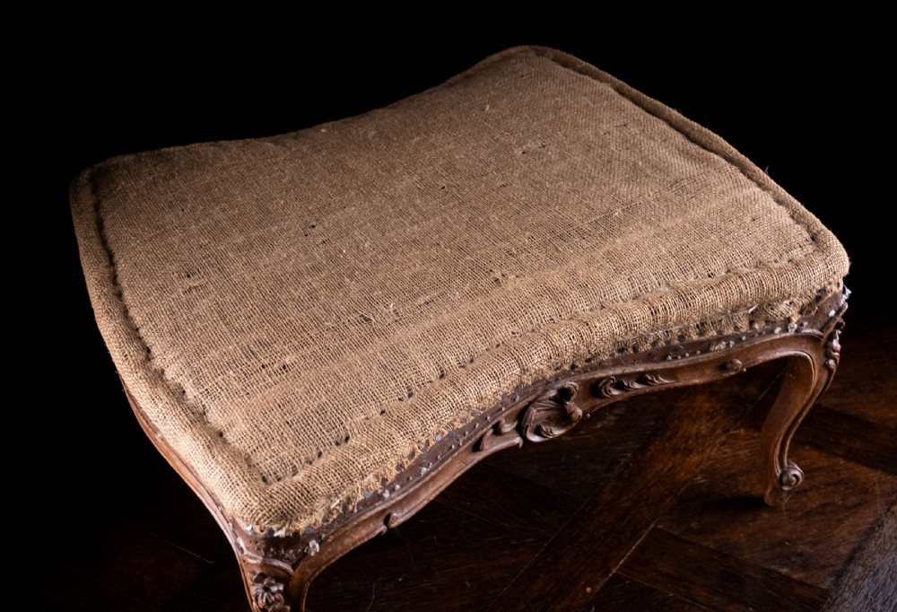 A low rectangular Louis XV style footstool featuring a carved beech frame, cabriole legs, shell motifs, and hessian upholstery. View XIV