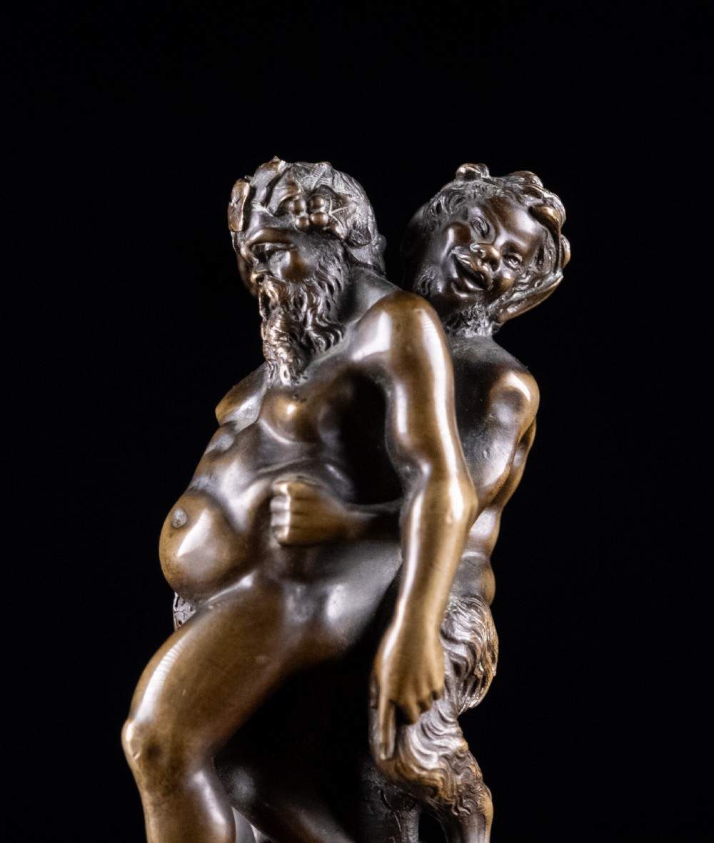 A dark brown bronze figurative sculpture group depicting Silenus supported by Pan and a Nereid on a textured bronze base. View V