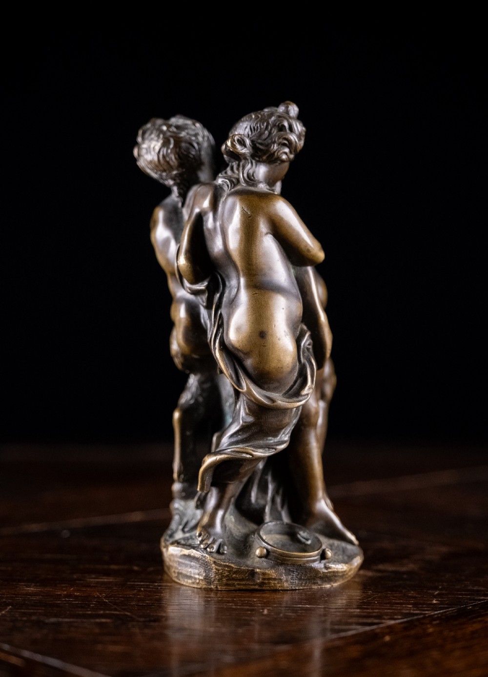 A dark brown bronze figurative sculpture group depicting Silenus supported by Pan and a Nereid on a textured bronze base. View IX