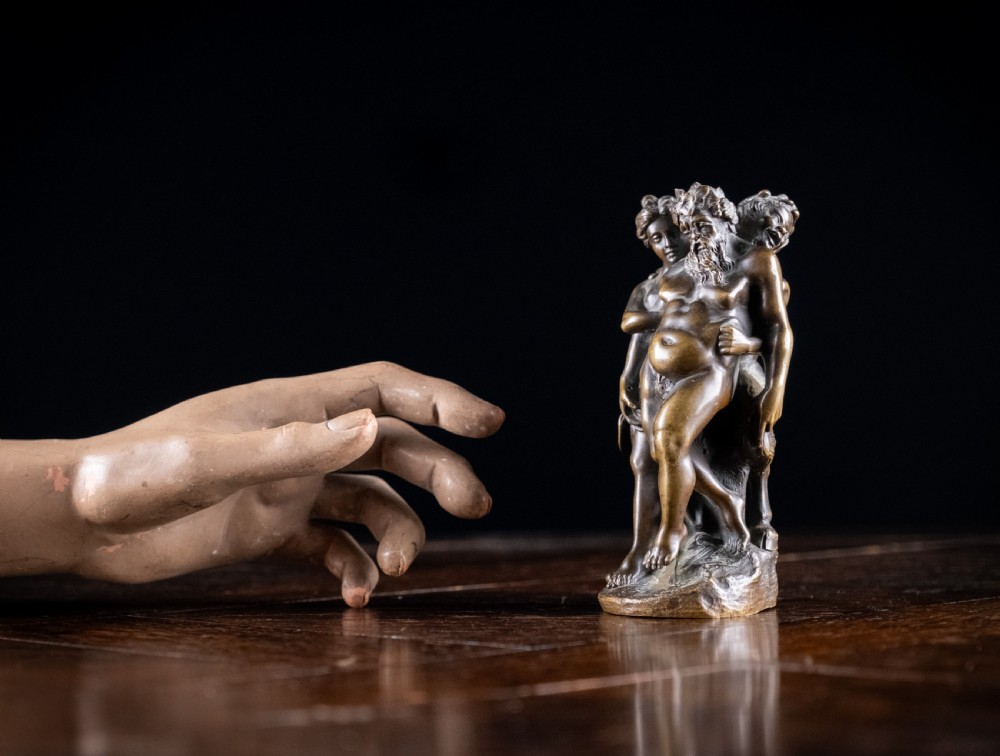 A dark brown bronze figurative sculpture group depicting Silenus supported by Pan and a Nereid on a textured bronze base. View XII