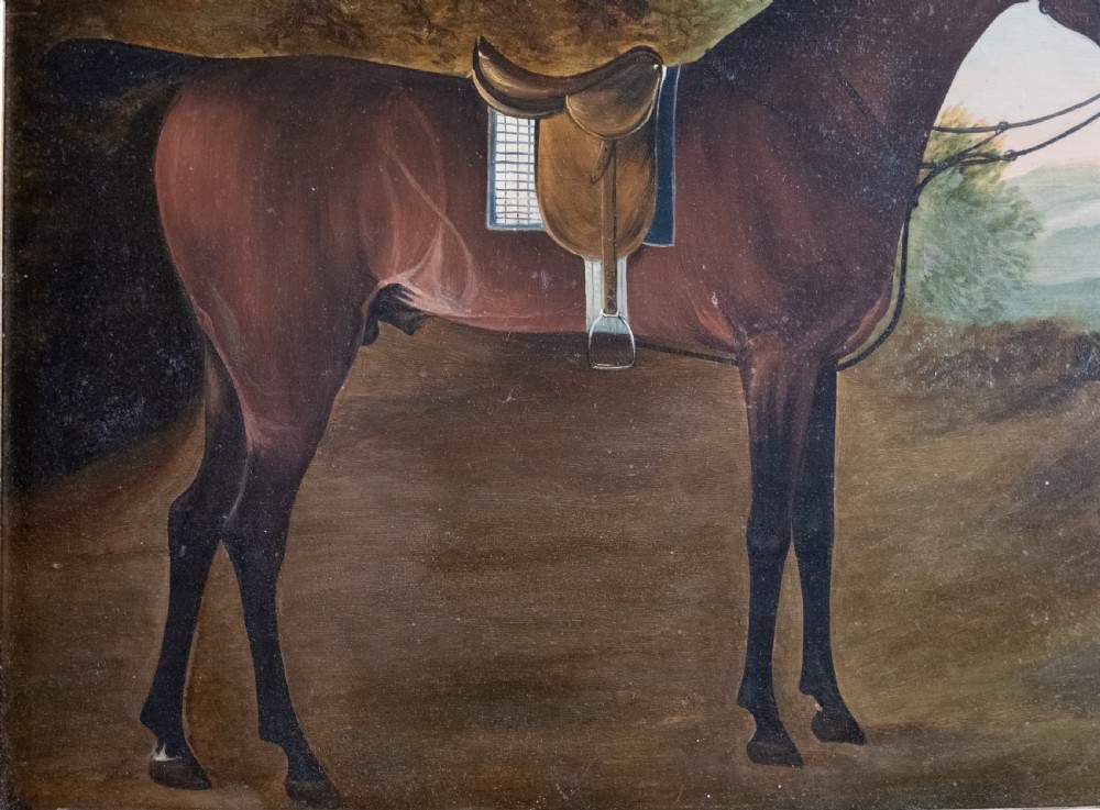 Early 19th-century oil painting on board depicting a saddled bay hunter horse standing in profile within a rural landscape, presented in a light wood frame. View III