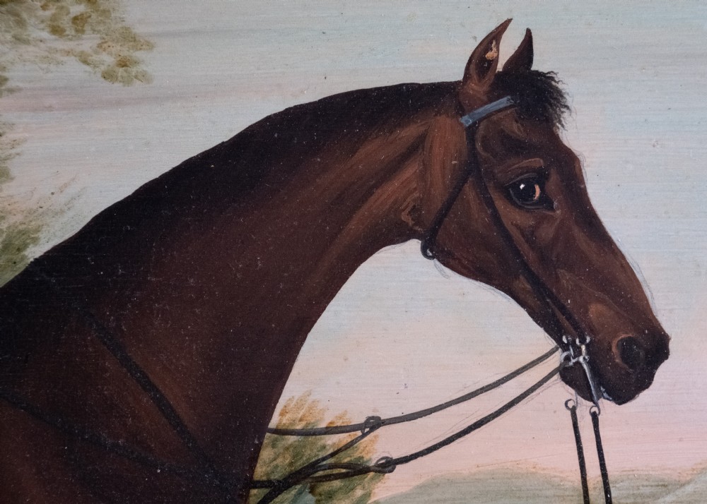 Early 19th-century oil painting on board depicting a saddled bay hunter horse standing in profile within a rural landscape, presented in a light wood frame. View V