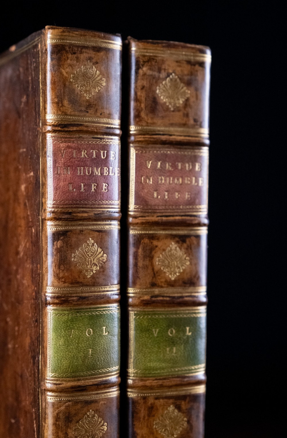 A two-volume set of 18th-century calfskin leather-bound books displaying gilt-tooled spines with red and green title labels. View II