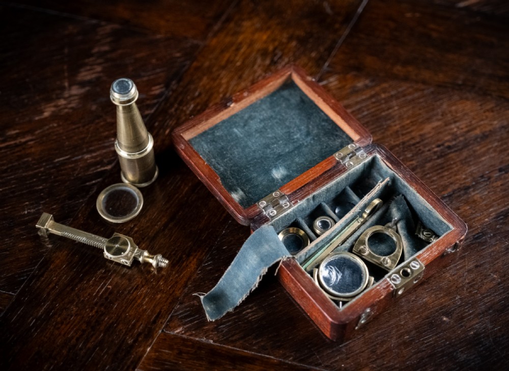A small early 19th-century lacquered brass pocket microscope mounted onto the rim of its fitted mahogany storage box. View VIII