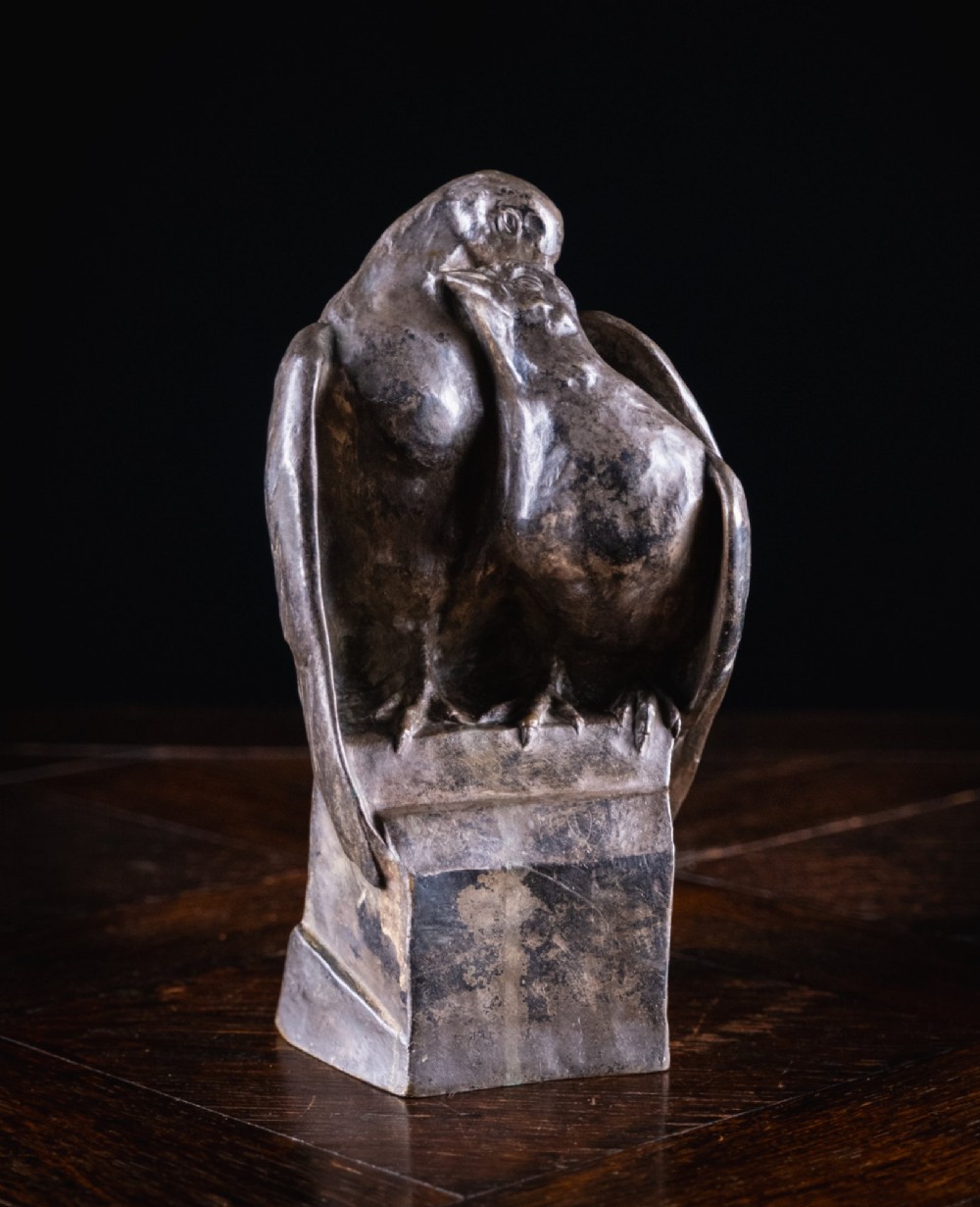 A dark nickel bronze sculpture depicting two stylised pigeons resting together on an integrated rectangular base.