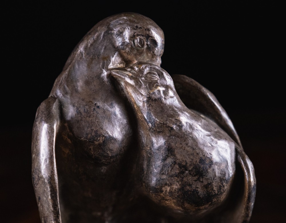 A dark nickel bronze sculpture depicting two stylised pigeons resting together on an integrated rectangular base. View III