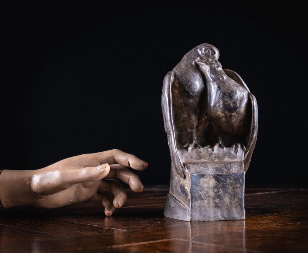 A dark nickel bronze sculpture depicting two stylised pigeons resting together on an integrated rectangular base. View IX