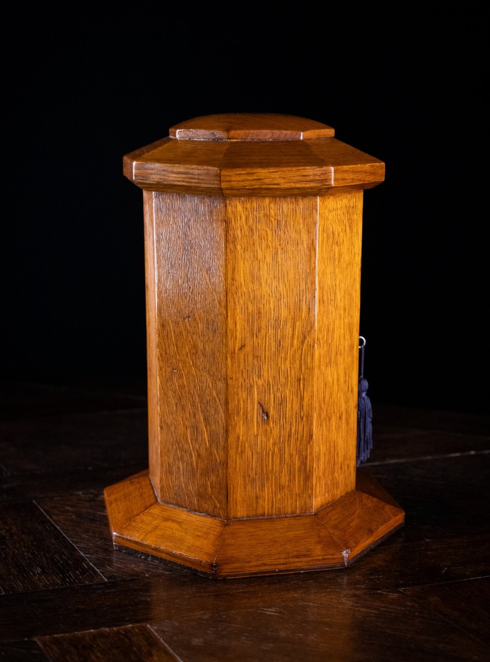An octagonal oak tabletop post box featuring a brass letter slot marked LETTERS and a key-locked front door with a collection schedule frame. View V
